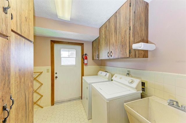 5111 Coral Blvd, Bradenton, FL 34210 - laundry area with cabinet space, washing machine and clothes dryer, tile walls, a wainscoted wall, and a textured ceiling