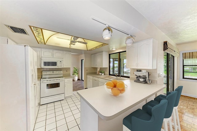 5111 Coral Blvd, Bradenton, FL 34210 - kitchen with white appliances, a peninsula, plenty of natural light, white cabinetry, and a textured ceiling