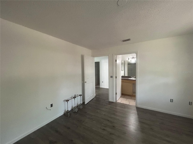 unfurnished room featuring wood finished floors, baseboards, and a textured ceiling