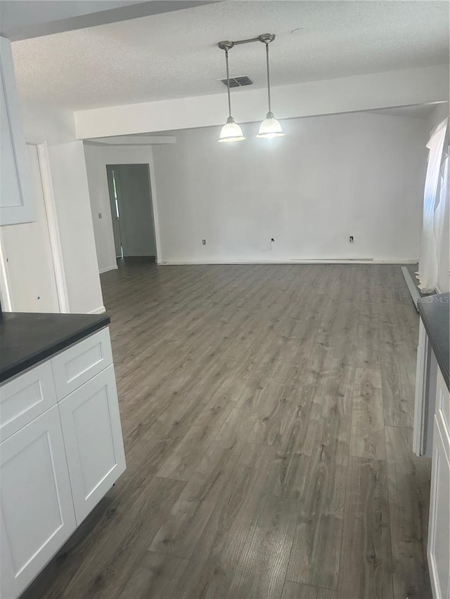 unfurnished dining area featuring dark wood-type flooring and a textured ceiling