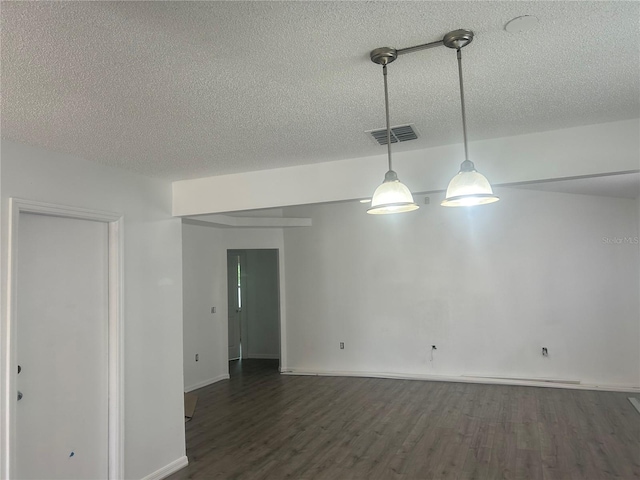 empty room featuring a textured ceiling, dark wood-style flooring, and baseboards