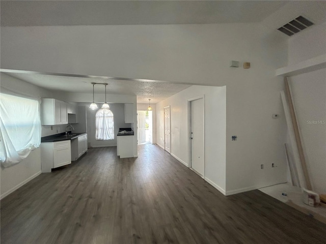 kitchen featuring a sink, dark wood finished floors, dark countertops, white cabinetry, and baseboards