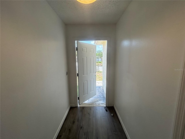 doorway to outside featuring baseboards, a textured ceiling, and dark wood-style flooring