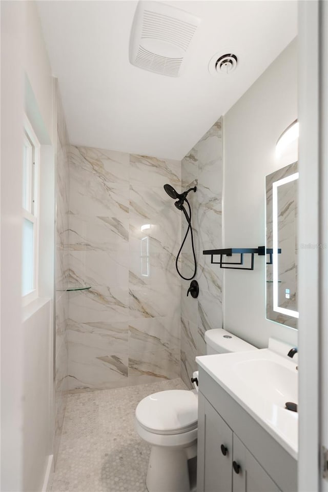 bathroom with tiled shower, toilet, and vanity