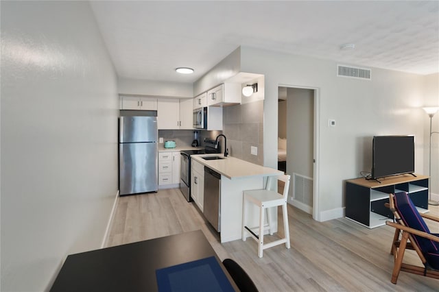 kitchen with light hardwood / wood-style floors, white cabinetry, and stainless steel appliances