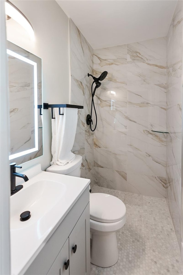 bathroom featuring tiled shower, toilet, and vanity