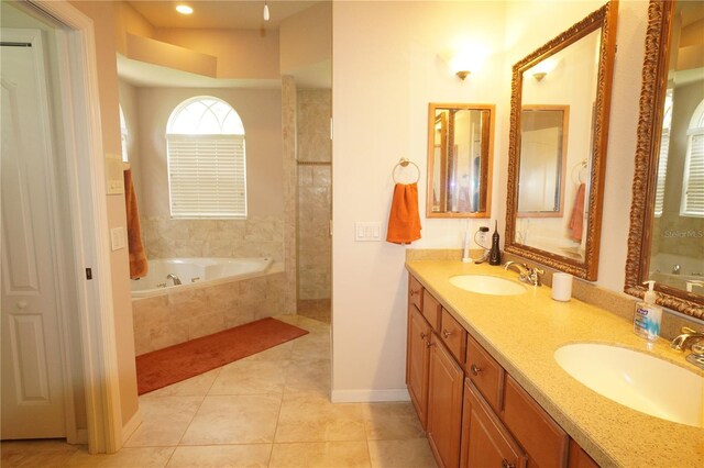 bathroom with dual vanity, tiled tub, and tile patterned flooring