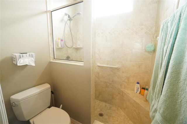 bathroom featuring a tile shower, a healthy amount of sunlight, and toilet