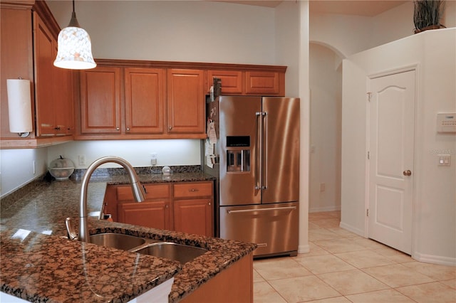 kitchen with dark stone countertops, light tile patterned floors, sink, decorative light fixtures, and high end refrigerator