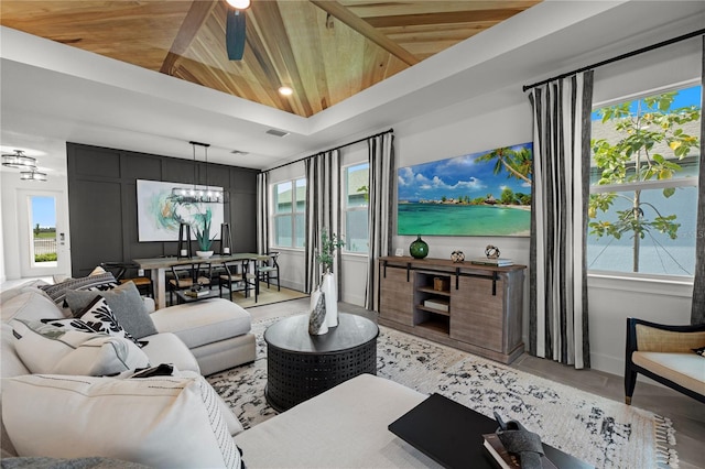 living room featuring an inviting chandelier, wooden ceiling, and a raised ceiling