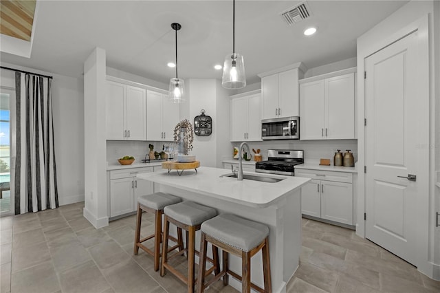 kitchen featuring sink, white cabinetry, stainless steel appliances, and a center island with sink