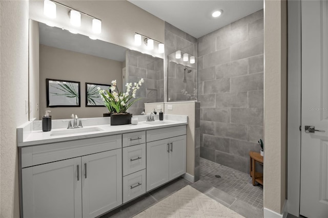 bathroom featuring dual vanity, a tile shower, and tile patterned floors