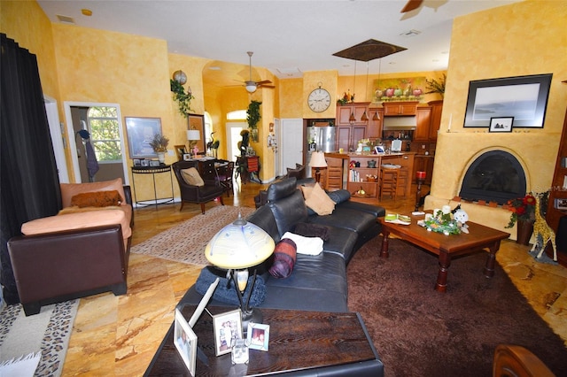 tiled living room with a fireplace and ceiling fan