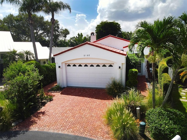 view of front of house featuring a tiled roof, decorative driveway, an attached garage, and stucco siding