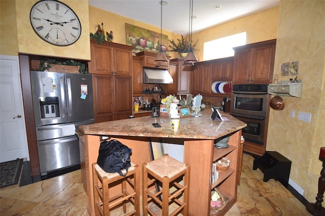 kitchen with appliances with stainless steel finishes, light tile patterned floors, light stone countertops, a kitchen breakfast bar, and a center island