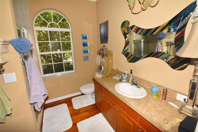 bathroom with a chandelier, hardwood / wood-style flooring, toilet, and vanity