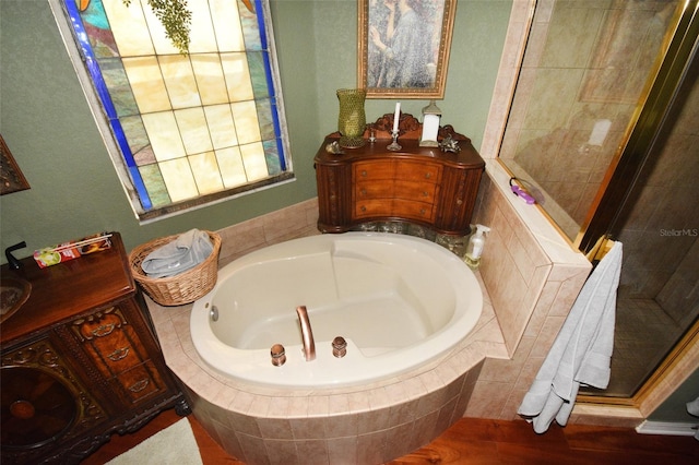 bathroom featuring vanity, hardwood / wood-style flooring, and tiled bath