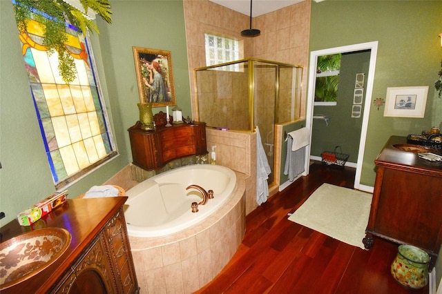 bathroom featuring plus walk in shower, vanity, a wealth of natural light, and hardwood / wood-style floors