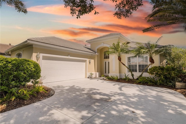 mediterranean / spanish home featuring driveway, an attached garage, and stucco siding