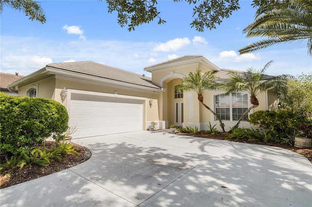 mediterranean / spanish-style house featuring concrete driveway, an attached garage, and stucco siding