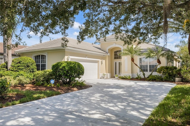 view of front of house featuring driveway, an attached garage, a tile roof, and stucco siding