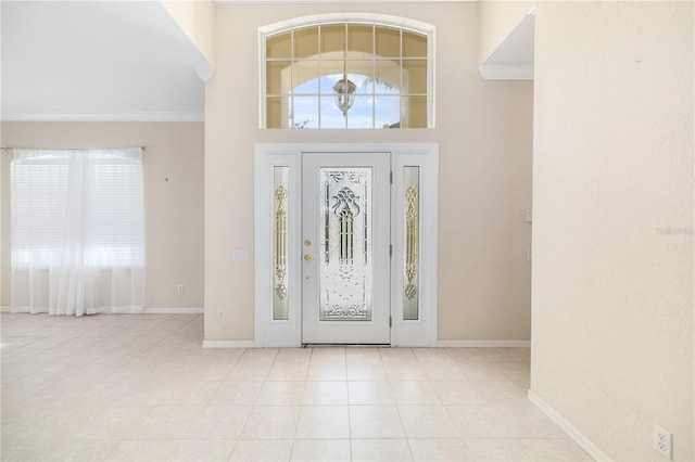 tiled foyer entrance featuring a towering ceiling and ornamental molding