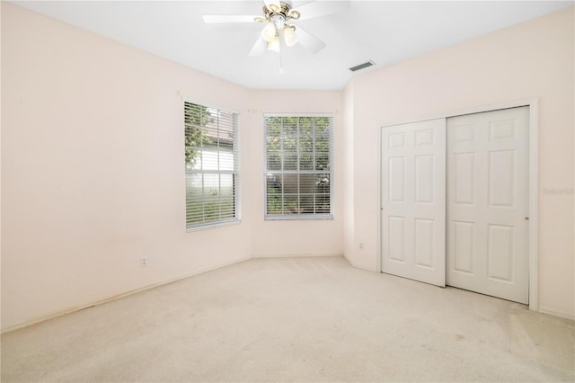 unfurnished bedroom featuring a closet, ceiling fan, and light colored carpet