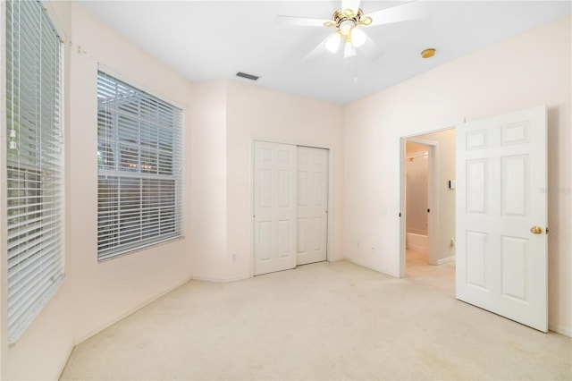 unfurnished bedroom featuring light colored carpet, a closet, and ceiling fan