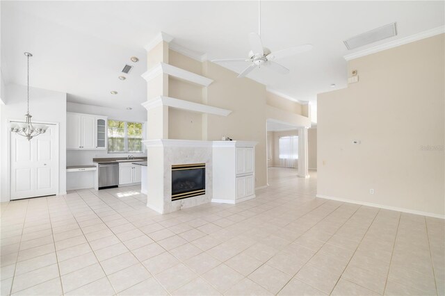 unfurnished living room with ceiling fan with notable chandelier, ornamental molding, sink, a premium fireplace, and light tile patterned floors