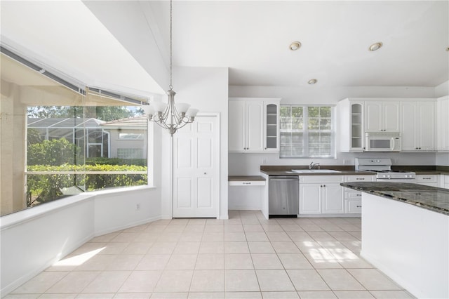 kitchen with white appliances, a wealth of natural light, light tile patterned floors, white cabinets, and hanging light fixtures