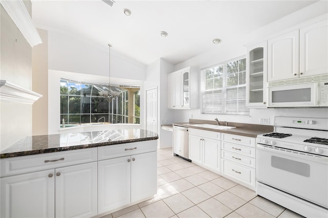 kitchen featuring white appliances, white cabinets, dark stone counters, vaulted ceiling, and sink