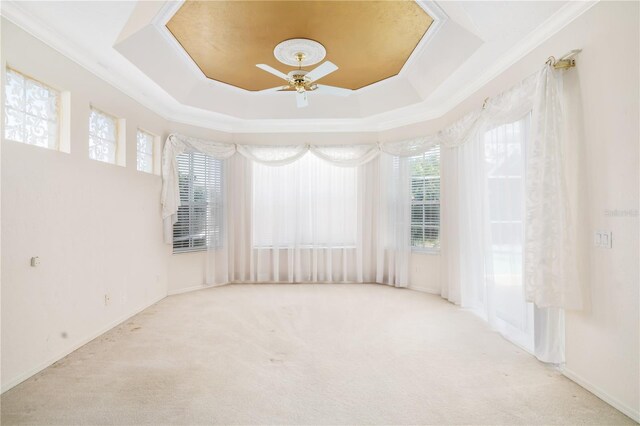 unfurnished room with ornamental molding, light carpet, ceiling fan, and a tray ceiling