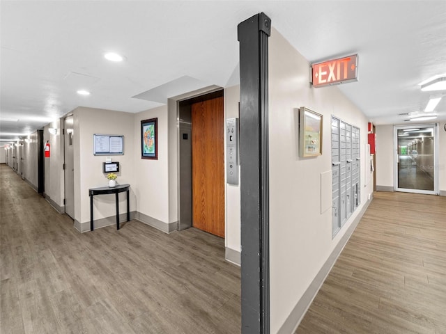 corridor featuring elevator, mail boxes, and light wood-type flooring