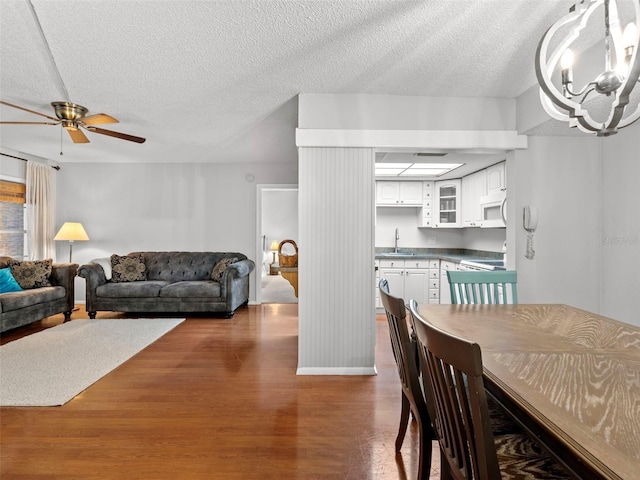 dining area featuring sink, a textured ceiling, dark wood-type flooring, and ceiling fan