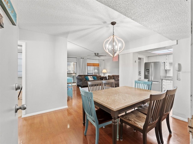 dining area featuring ceiling fan with notable chandelier, light hardwood / wood-style flooring, and a textured ceiling