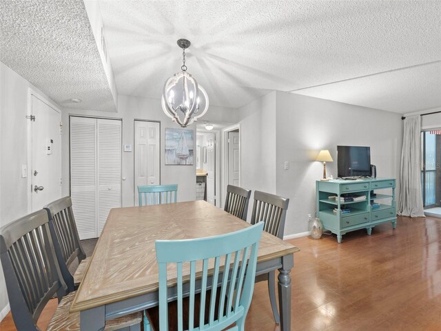 dining space featuring wood-type flooring, a chandelier, and a textured ceiling