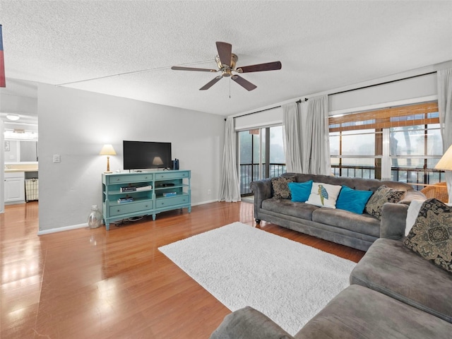 living room featuring ceiling fan, a textured ceiling, and light hardwood / wood-style flooring