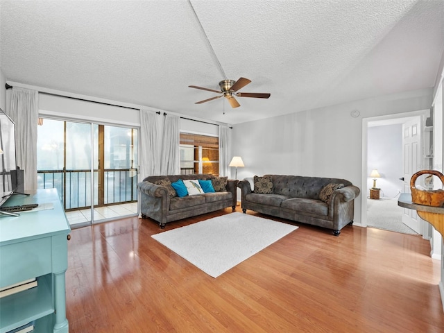 living room featuring ceiling fan, light hardwood / wood-style floors, and a textured ceiling