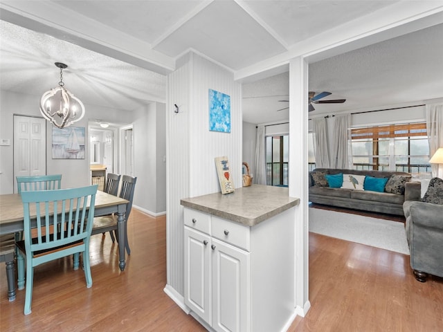 kitchen featuring hanging light fixtures, white cabinetry, ceiling fan with notable chandelier, and light hardwood / wood-style floors