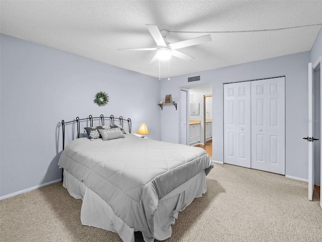 carpeted bedroom featuring connected bathroom, ceiling fan, a closet, and a textured ceiling