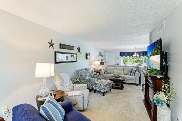 living room with light carpet, a textured ceiling, and a notable chandelier