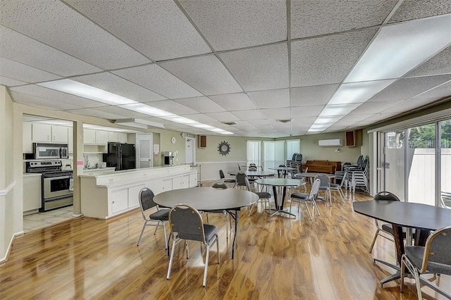 dining area with a drop ceiling and light hardwood / wood-style floors