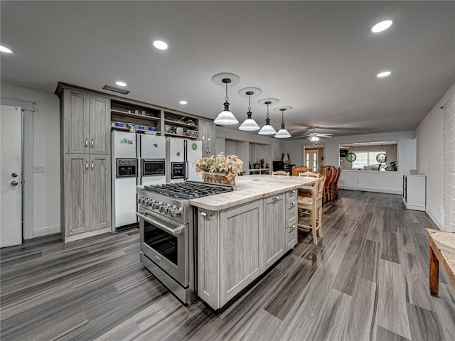 kitchen with ceiling fan, pendant lighting, a kitchen island, high end stainless steel range, and dark wood-type flooring