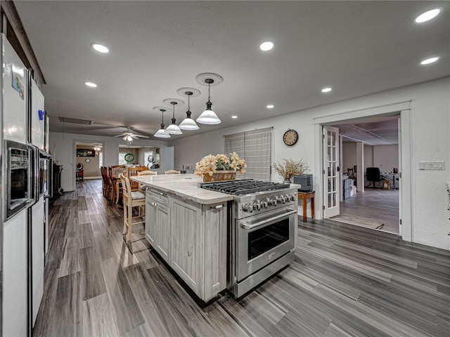 kitchen featuring high end stove, ceiling fan, white cabinets, and hardwood / wood-style floors