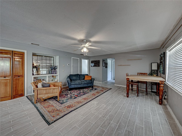 living room with light hardwood / wood-style flooring, a textured ceiling, and ceiling fan