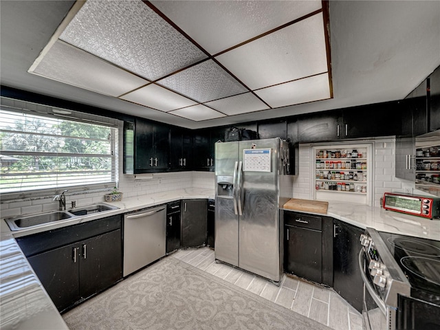 kitchen featuring tasteful backsplash, stainless steel appliances, sink, light stone counters, and light tile patterned floors