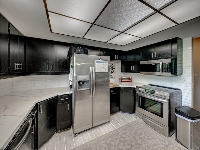 kitchen featuring light carpet, a drop ceiling, backsplash, and stainless steel appliances