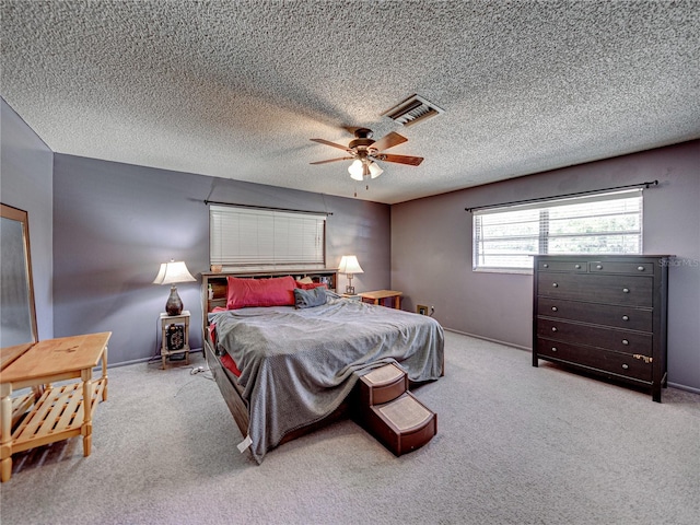 bedroom featuring a textured ceiling, ceiling fan, and light colored carpet