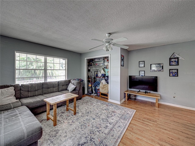 living room with light hardwood / wood-style floors, a textured ceiling, and ceiling fan