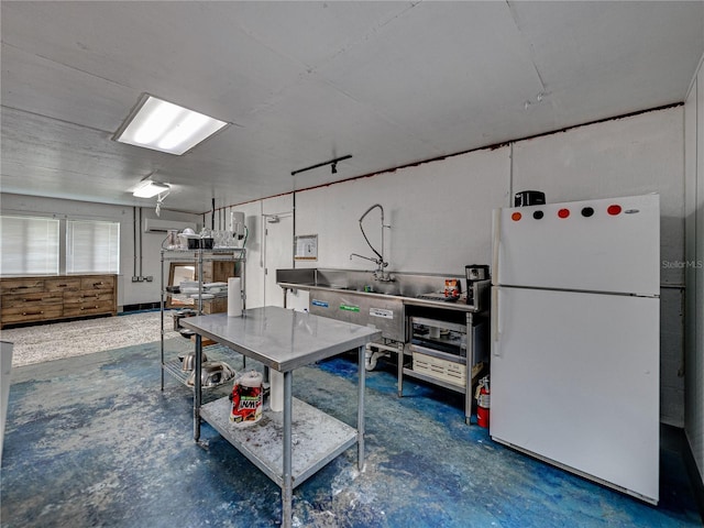 kitchen with concrete floors, white fridge, and a wall unit AC